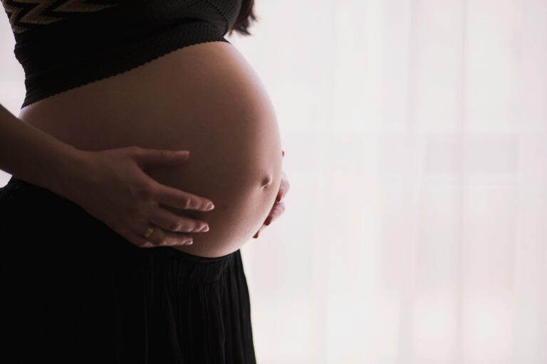 a pregnant woman holds her belly after taking tylenol during pregnancy