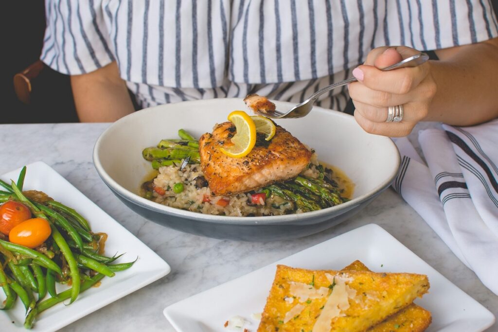 Woman eats salmon over rice and asparagus after considering what to eat after intermittent fasting
