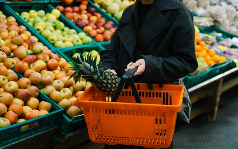 Shopper placing a pineapple in a grocery basket, one of the low-pesticide picks on the Clean Fifteen list