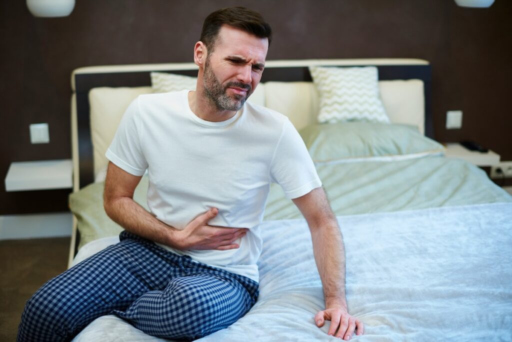 a man holds his stomach as it's upset from a Cyclospora oubreak