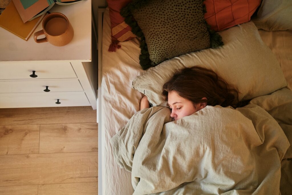 a woman sleeping peacefully under a soft blanket, illustrating how cannabis and sleep quality are connected