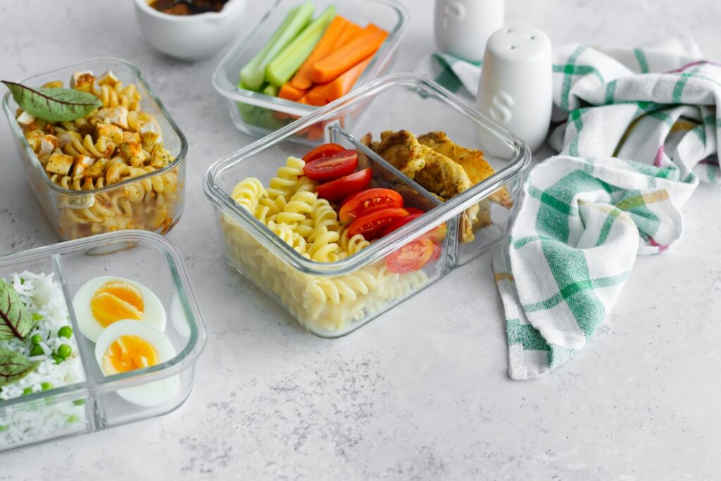 Glass meal prep containers with pasta, chicken, and vegetables, a safer swap for how to avoid microplastics in the kitchen