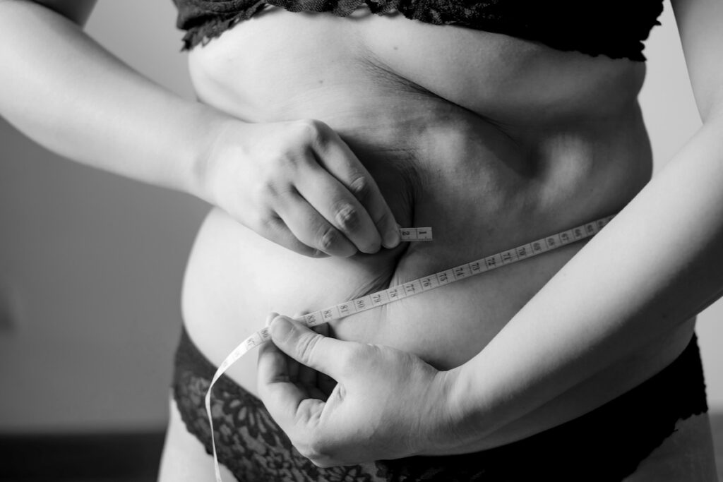 Woman measuring her waist with a tape measure, illustrating retatrutide weight loss results.