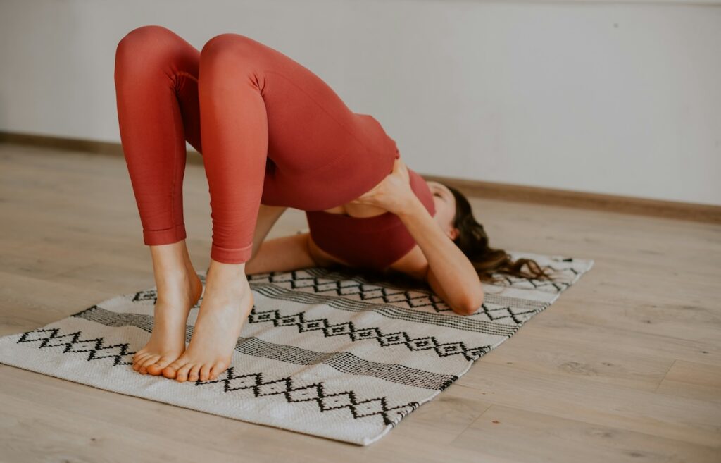 Woman raises hips into a glute bridge as part of a postpartum core workout.