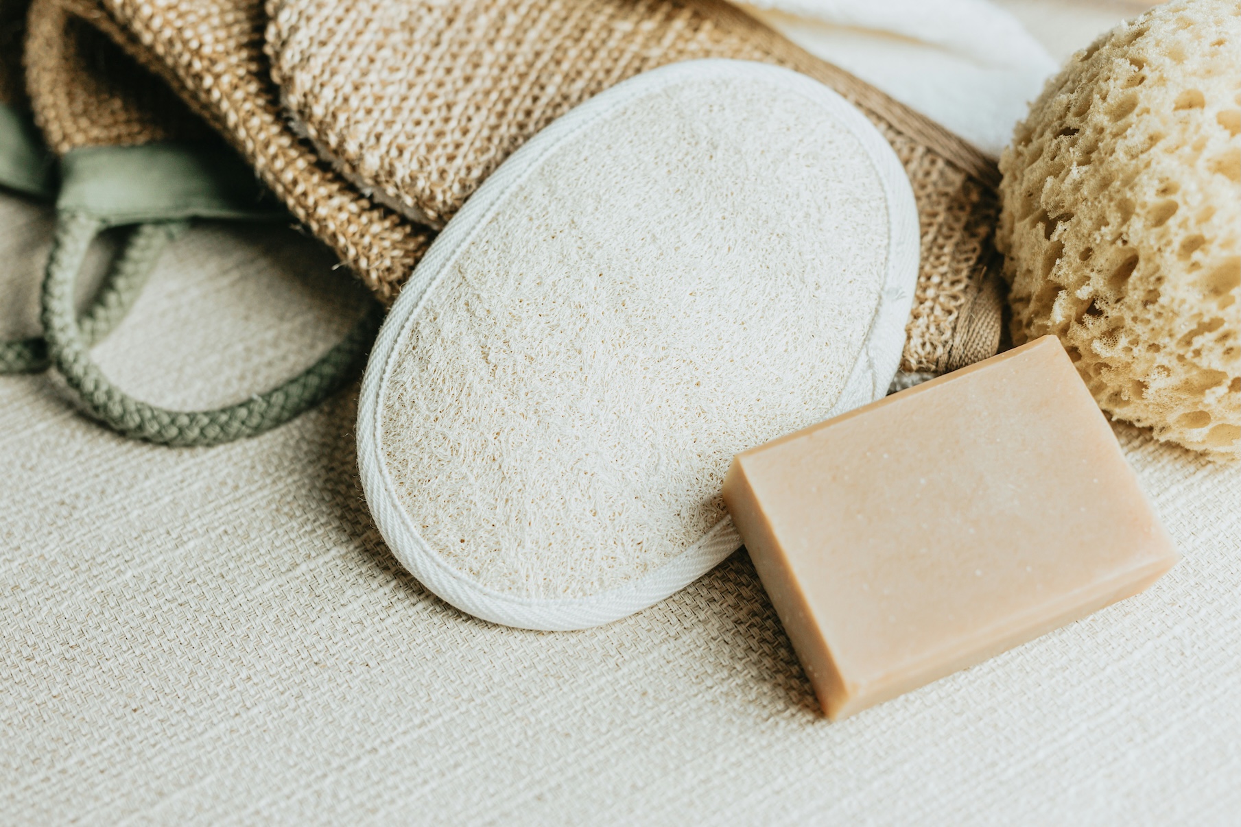 Loofah bacteria can build up in natural sponges like this one, shown here beside a bar of soap and woven bath accessories.