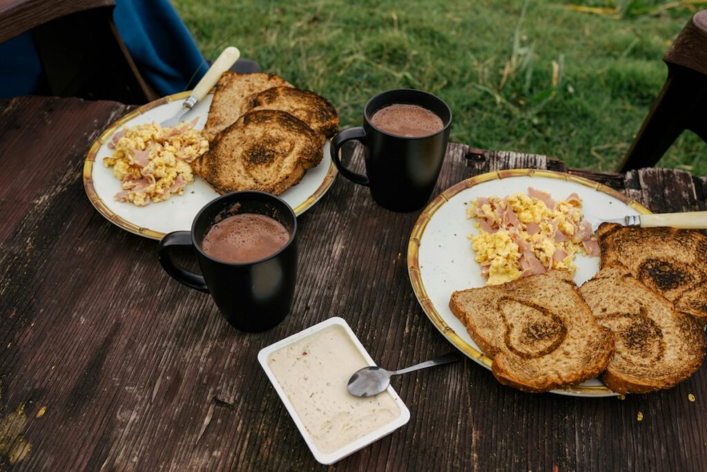 Breakfast plates with toast, scrambled eggs, and mugs, a scene tied to the coffee before or after breakfast debate