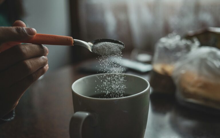 Spoon pouring sugar into a mug, illustrating the question of is sugar toxic