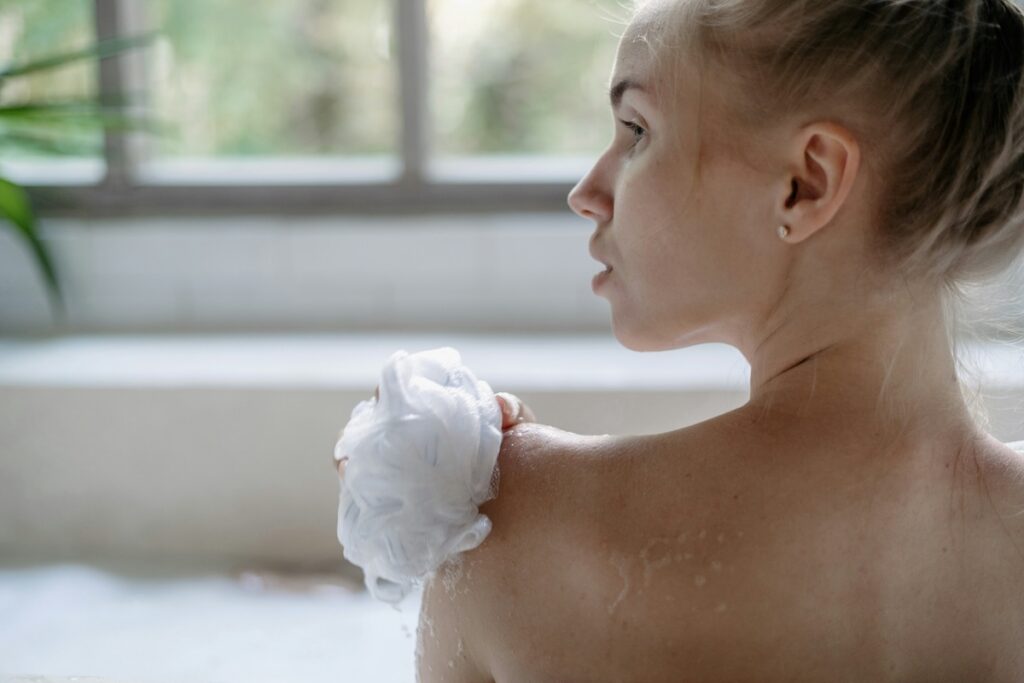 Loofah bacteria can accumulate on mesh puffs like this one, seen here as a woman washes her shoulder in the shower.