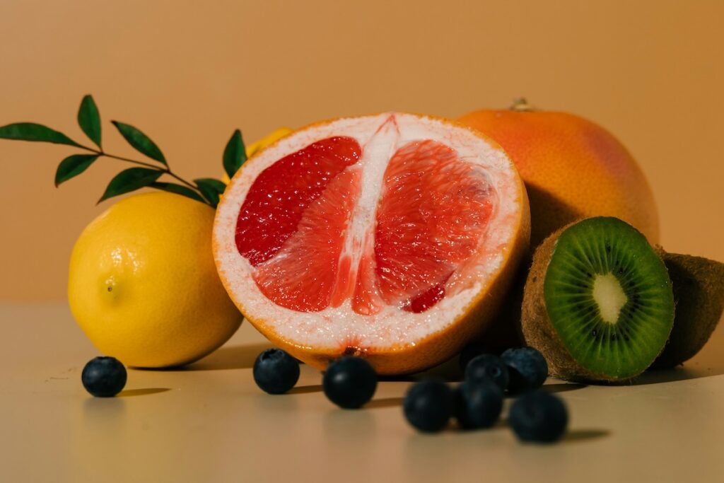 Low-calorie fruits including grapefruit, kiwi, lemon, and blueberries arranged on a countertop