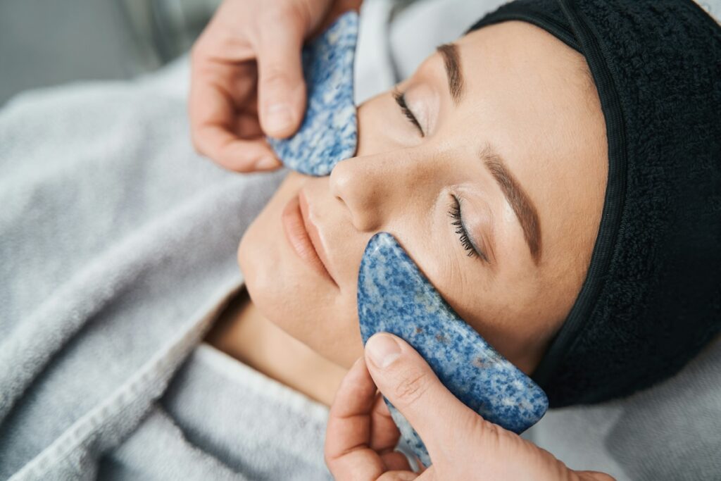 a woman uses lymphatic drainage techniques to reduce facial puffiness