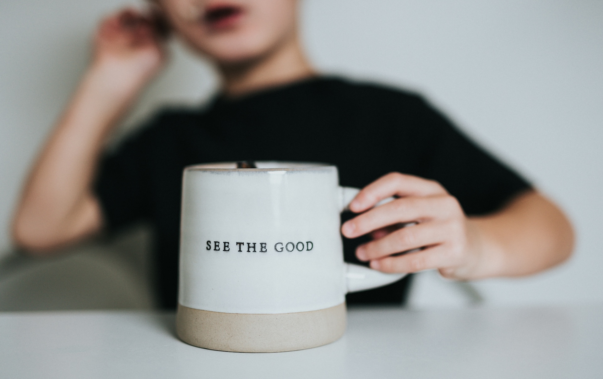 Person holding a mug that reads "See the Good," symbolizing an optimism and health mindset