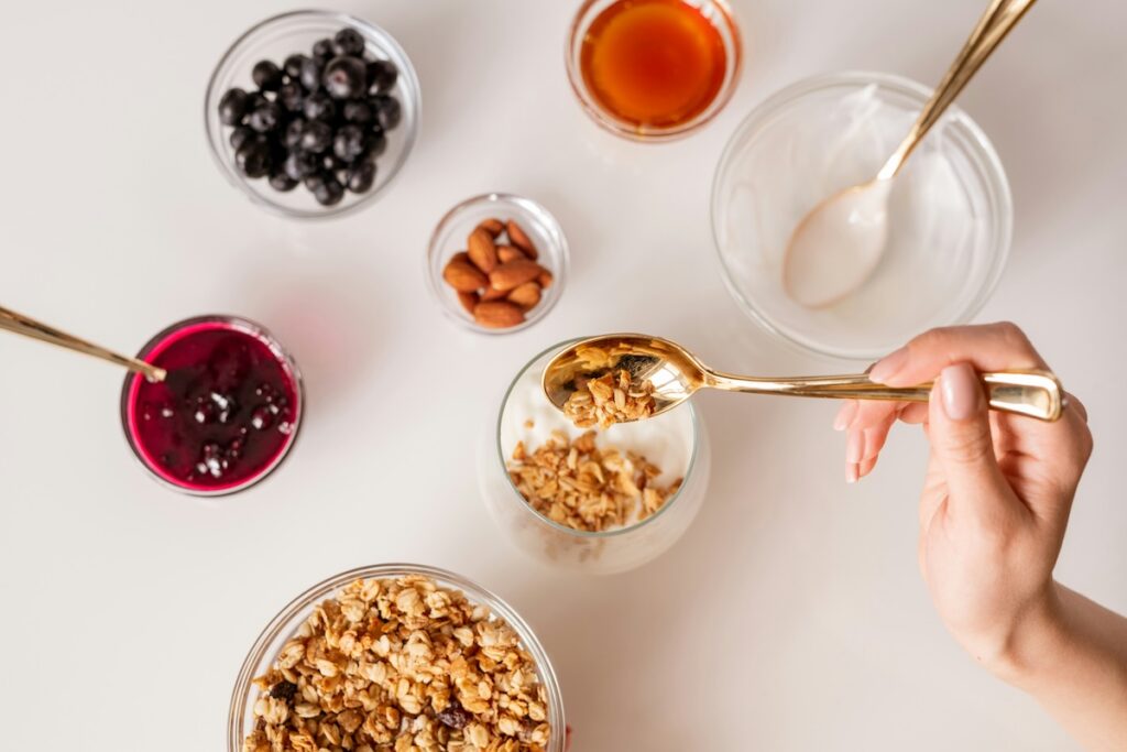 High-protein overnight oats ingredients including oats, yogurt, granola, almonds, blueberries, and honey