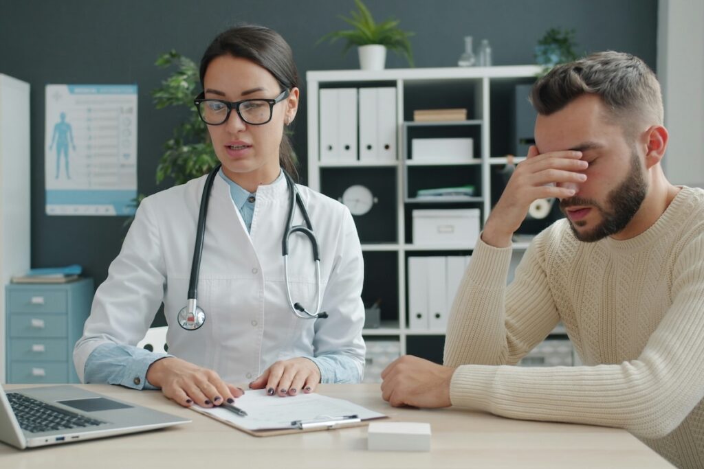 Man with headache consulting doctor about symptoms of low electrolytes