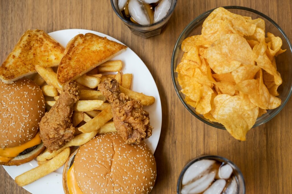 Fried food, burgers, chips, and soda plated together — examples of the worst foods for gut health