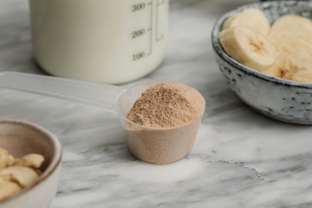Scoop of whey protein for aging muscles next to milk and sliced bananas