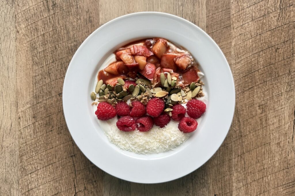 Peach compote yogurt bowl topped with raspberries, pumpkin seeds, granola, and shredded coconut, one of this week's easy meals under 30 minutes