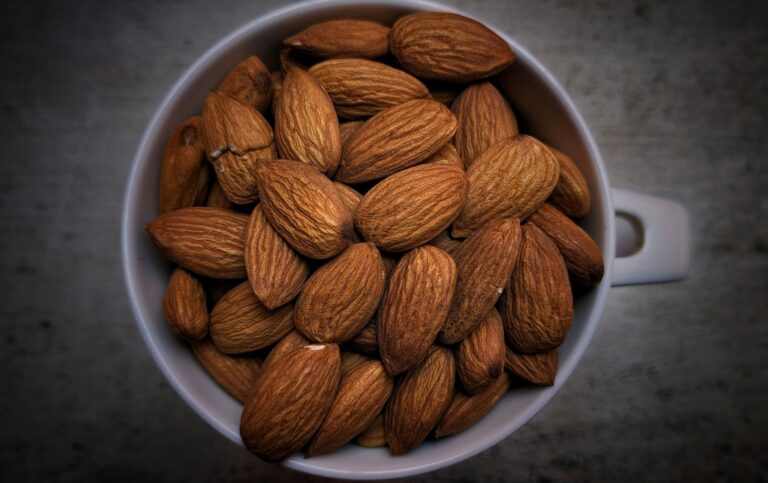 Overhead view of whole raw almonds filling a white mug, showcasing the healthiest nut you can eat