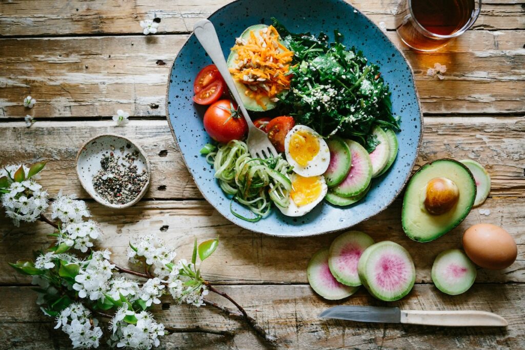 Balanced cortisol detox diet bowl with eggs, avocado, leafy greens, and vegetables on a wooden table