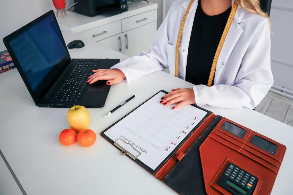Registered dietitian reviewing a weekly meal plan and laptop, helping guide a safe approach to intermittent fasting for women over 50