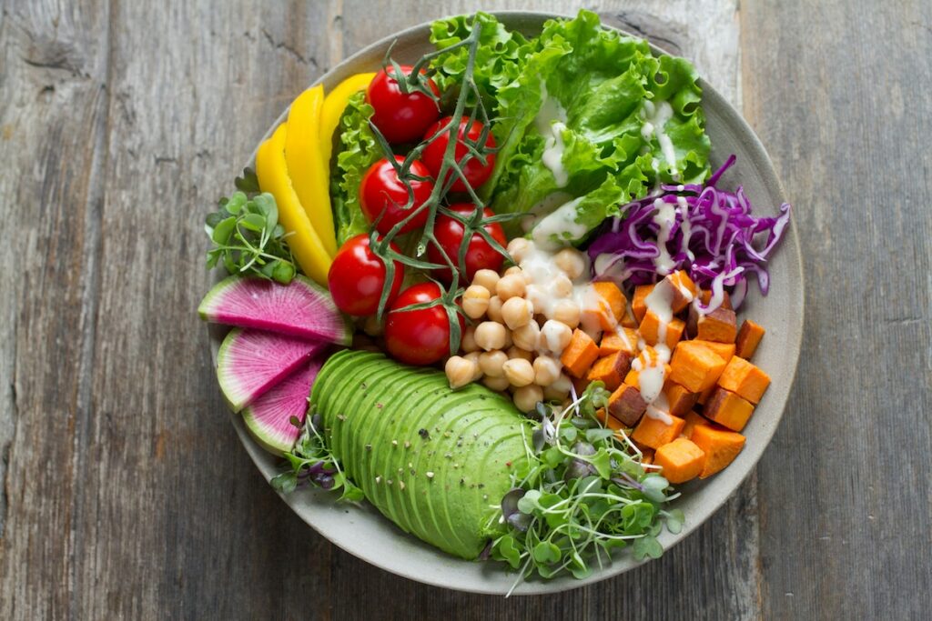 Bowl of how to get electrolytes foods including avocado, chickpeas, sweet potato, tomatoes, and leafy greens