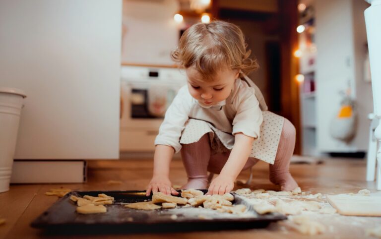 Toddler picking up cookie dough scraps off the kitchen floor, testing the five second rule