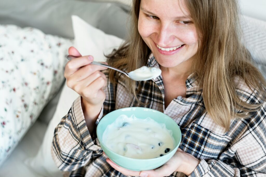 Woman enjoying a bowl of plain Greek yogurt, one of the best yogurt for gut health options