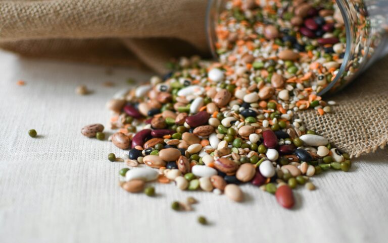Mixed dried beans and lentils spilling from a glass jar, examples of high protein high fiber foods