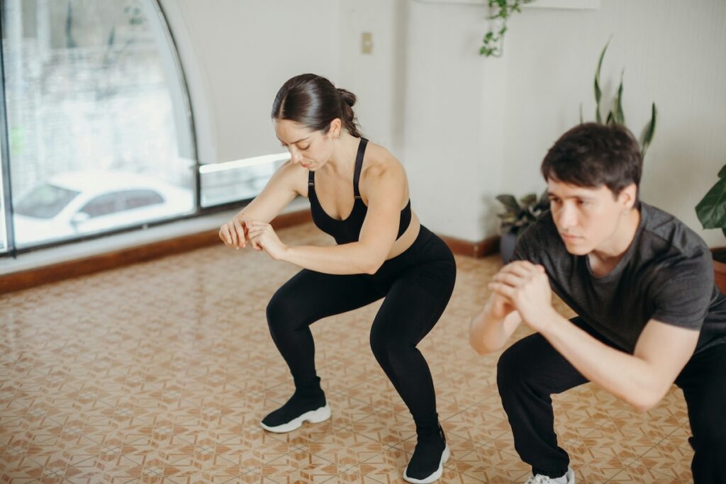 Man and woman performing a squat with arms extended for balance, similar to the sit-to-stand test used to assess fitness and aging
