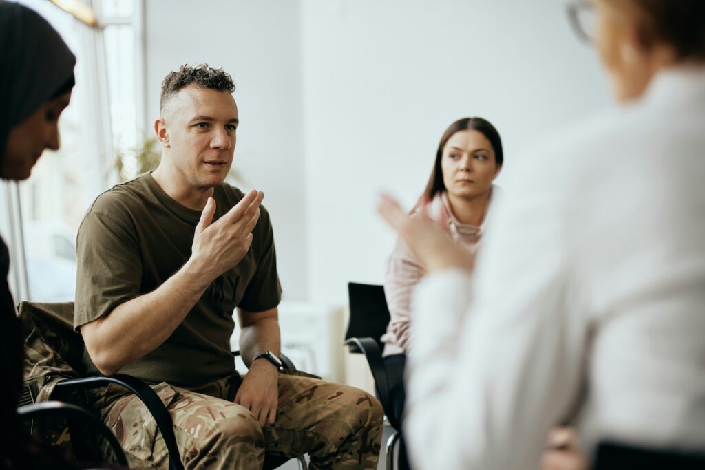 Veteran sharing his experience in a group discussion, illustrating PTSD talk therapy as a common but not always effective treatment approach.