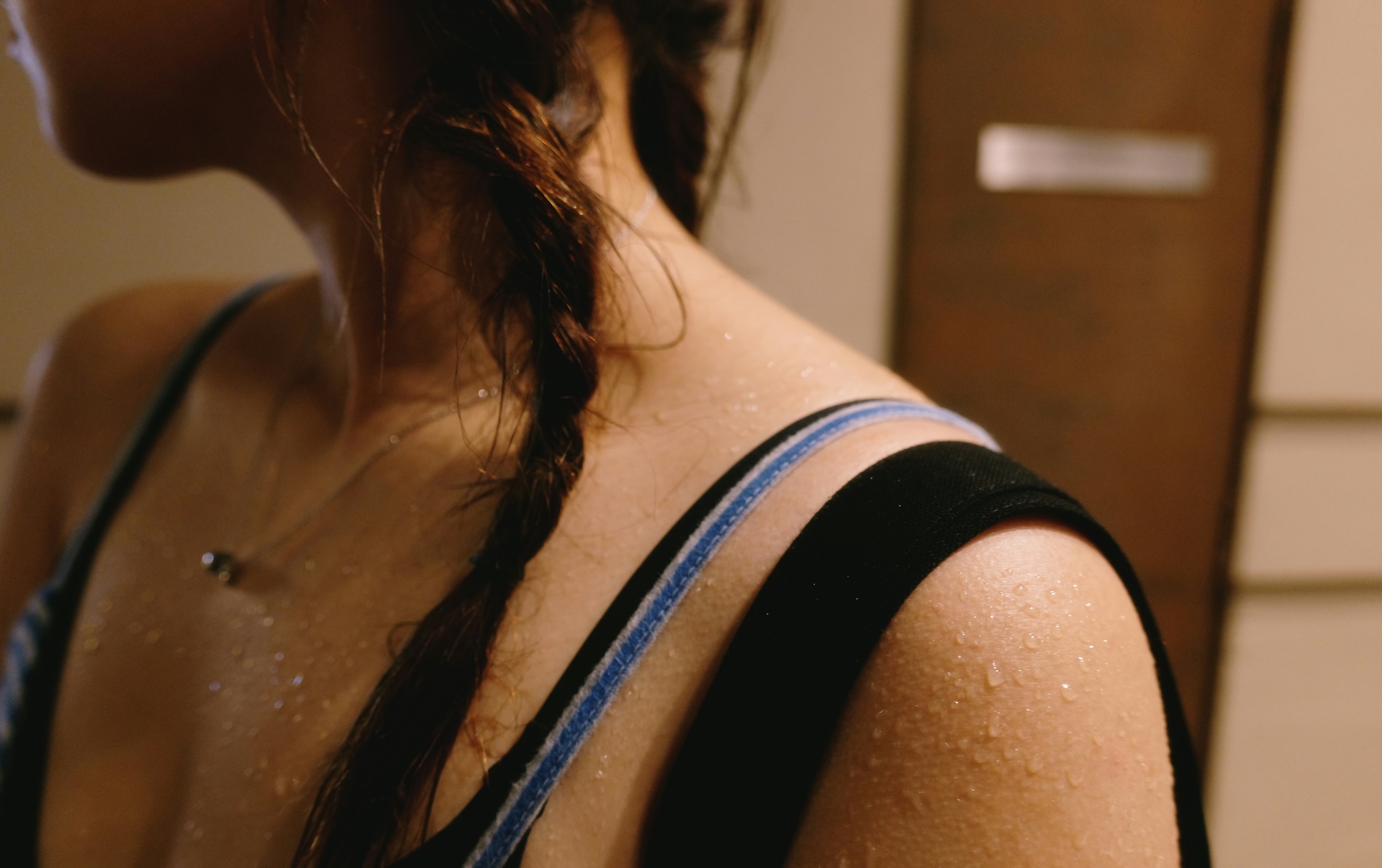 Close-up of sweat droplets on a woman's shoulder and collarbone after a workout, showing what your sweat can tell you about your health.