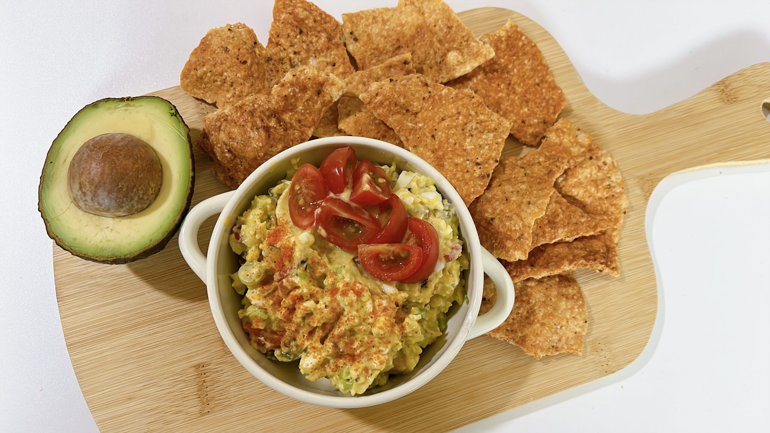 Ground chicken chips served with creamy avocado egg salad topped with cherry tomatoes and paprika