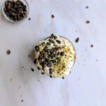 Chocolate smoothie topped with whipped cream, cacao nibs, and hemp seeds, seen from above