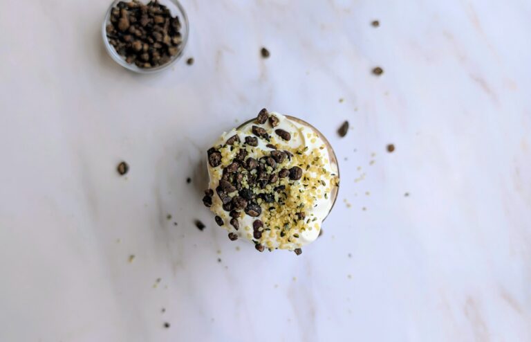 Chocolate smoothie topped with whipped cream, cacao nibs, and hemp seeds, seen from above