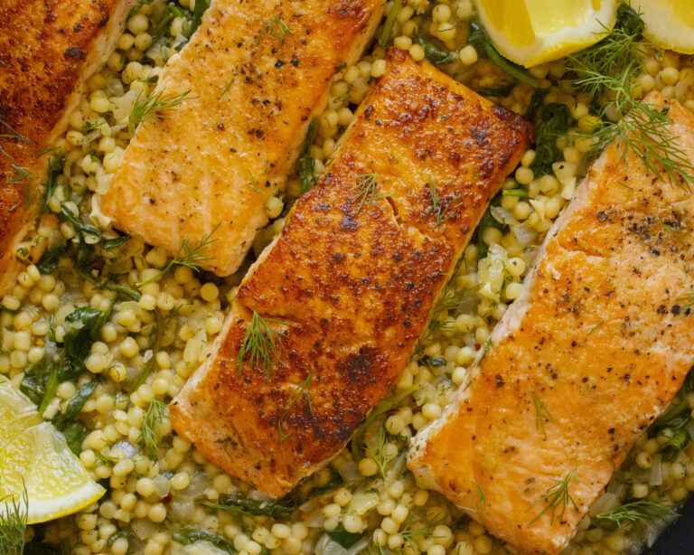 High protein meal prep: close-up of seared salmon over herby pearl couscous with dill and lemon, 42g protein