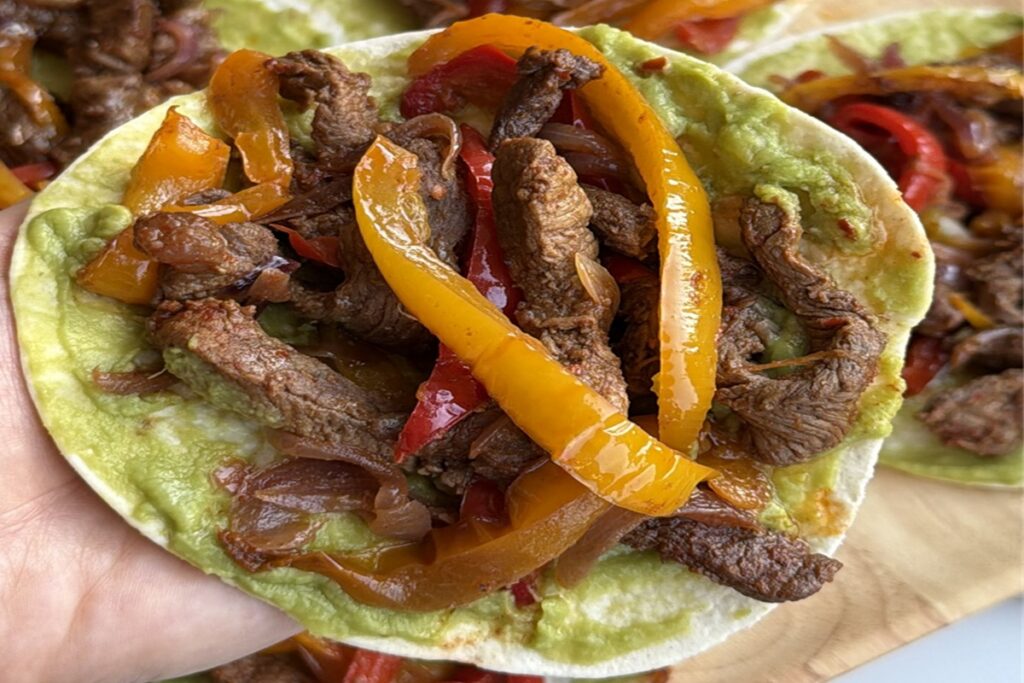 Steak fajitas with avocado sauce, peppers, and onions on tortillas, one of six simple healthy meals