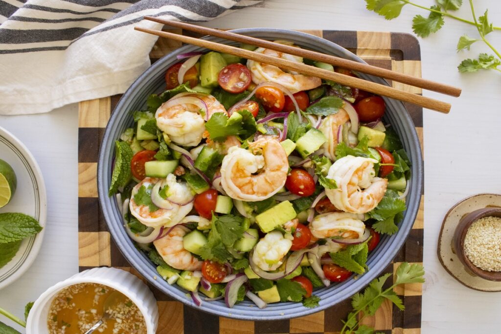 High protein meal prep idea: Vietnamese shrimp salad with avocado, cucumber, tomatoes, and herbs in a blue bowl