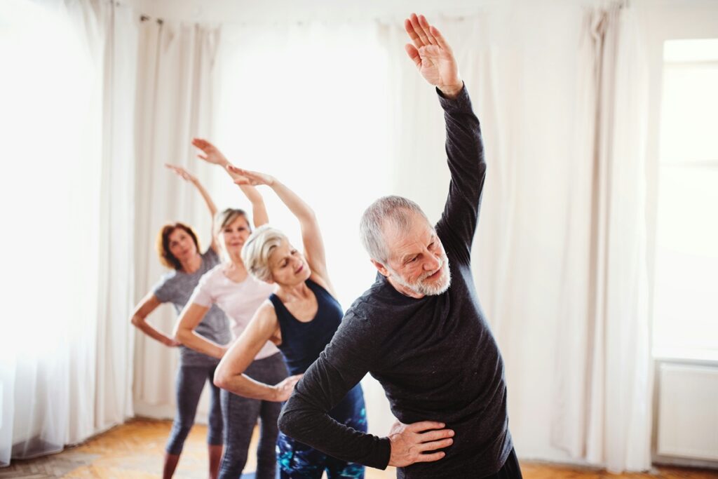 Group of older adults doing side stretches in an exercise class to help prevent age-related muscle loss