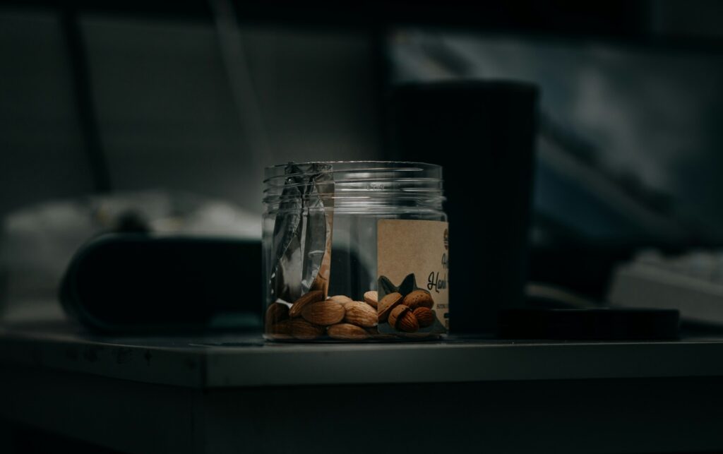 Small clear jar of whole almonds on a dimly lit bedside table at night, a simple evening snack linked to research on almonds for sleep