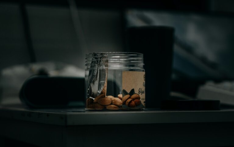 Small clear jar of whole almonds on a dimly lit bedside table at night, a simple evening snack linked to research on almonds for sleep
