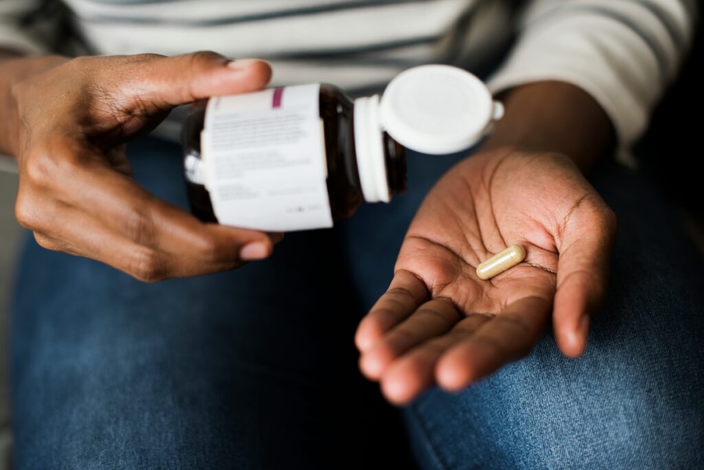 Person pouring a magnesium glycinate capsule into their hand from a supplement bottle, illustrating magnesium glycinate benefits