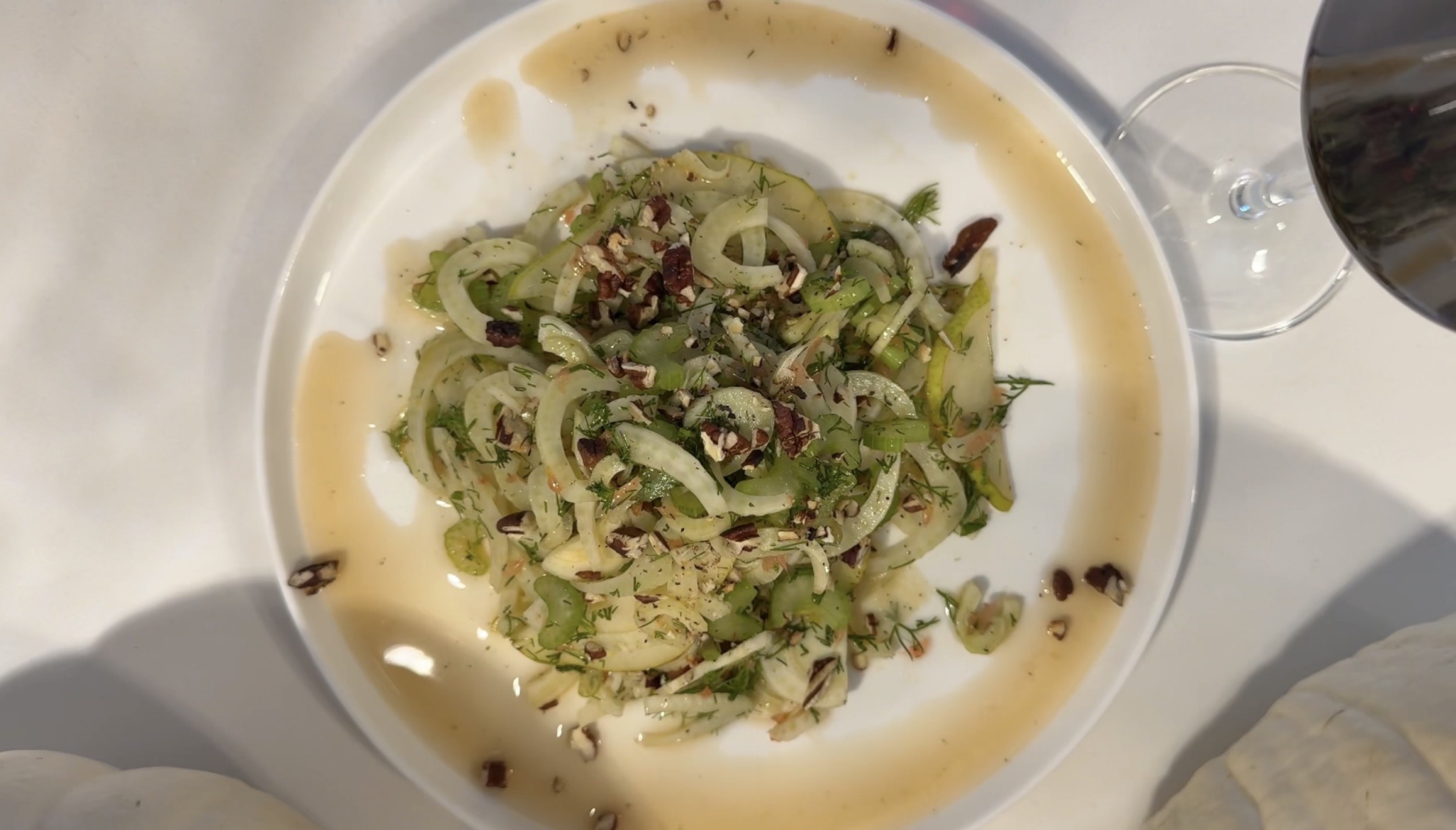 Shaved fennel salad with celery, pear, fresh dill, and chopped pecans in a honey citrus dressing on a white plate