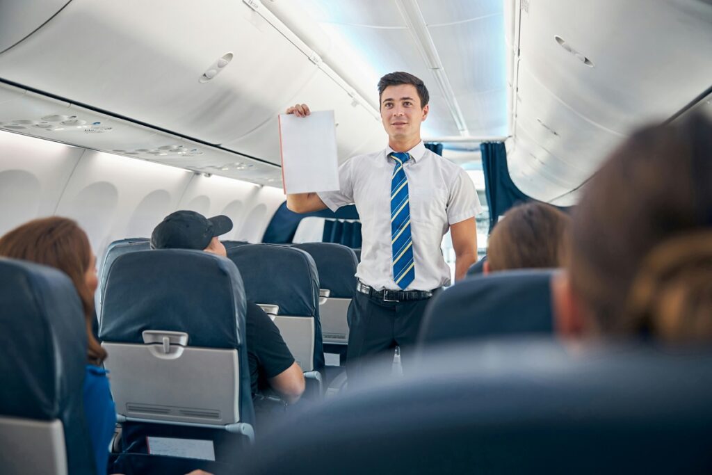 Flight attendant holding a safety card in the cabin, illustrating new research on flight crew cancer risk
