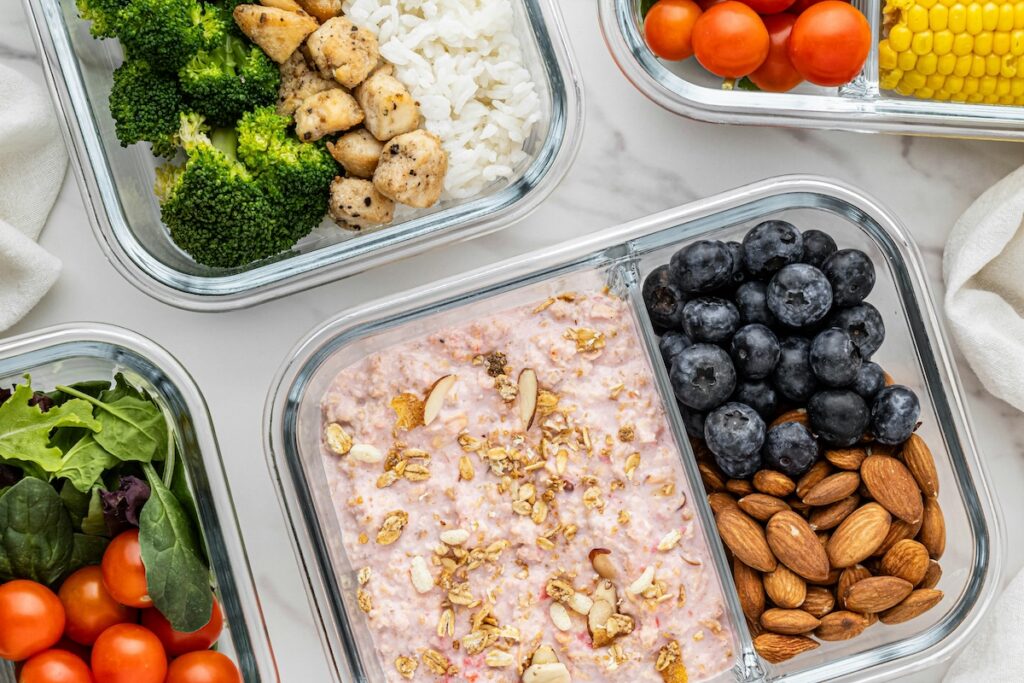 Foods that lower blood pressure in meal prep containers, including oats with blueberries, almonds, and leafy greens