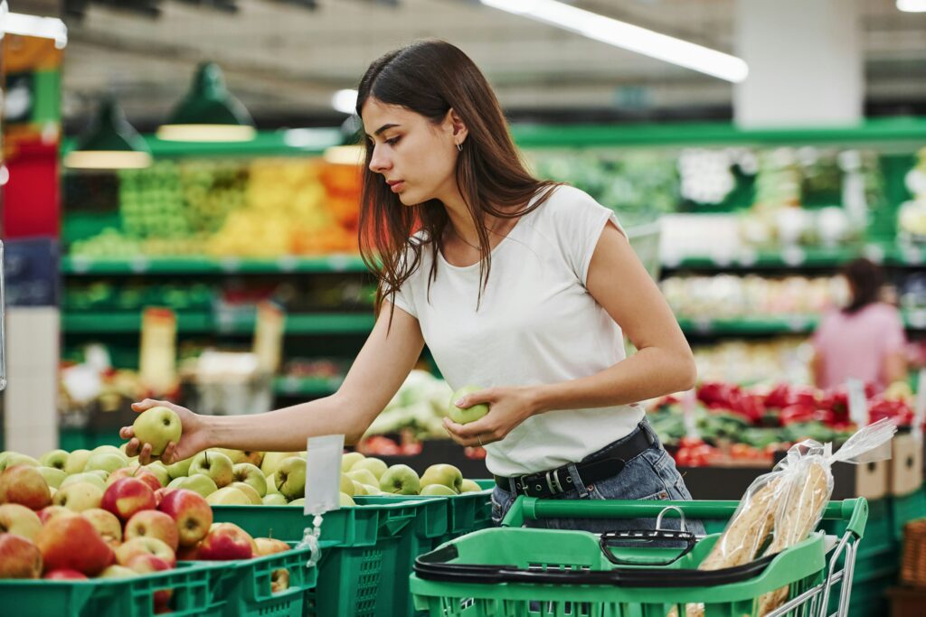 Woman choosing apples at a grocery store to find the healthiest types of apples