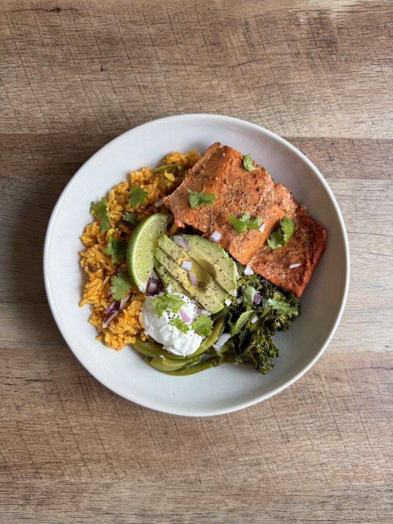 Salmon rice bowl with taco-seasoned salmon, Spanish rice, broccolini, avocado, and Greek yogurt