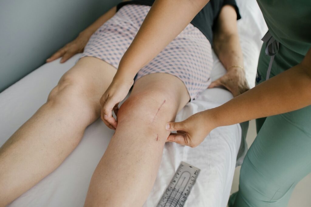Healthcare worker examining a patient’s swollen, red knee for signs of a blood clot