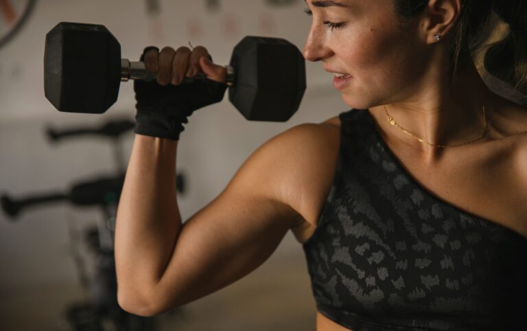 Woman doing a dumbbell bicep curl at the gym, showing the link between strength training and heart health in women
